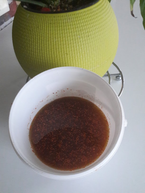 Huile d'olive versée dans un bocal contenant des herbes pour un macérât.